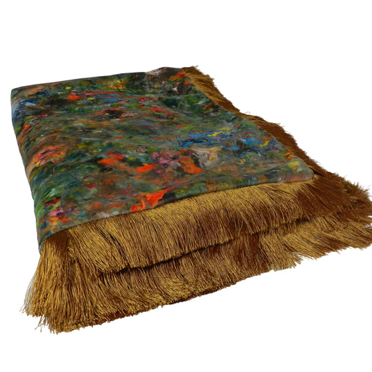 Textile with colorful abstract pattern and gold fringe on a white background